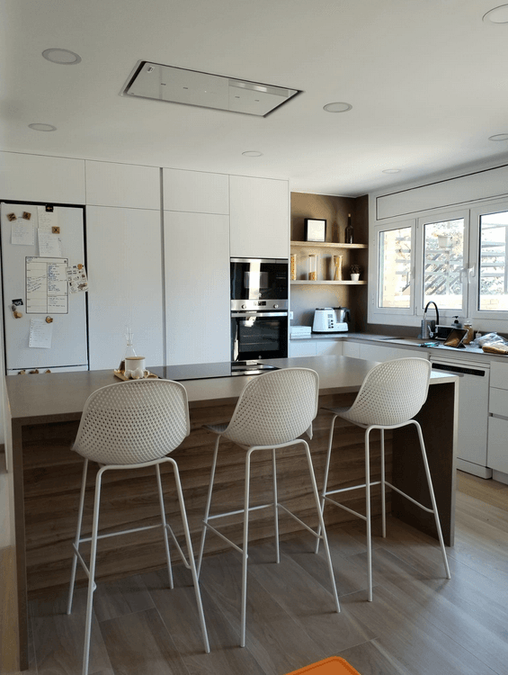 Cocina moderna con isla central y taburetes blancos