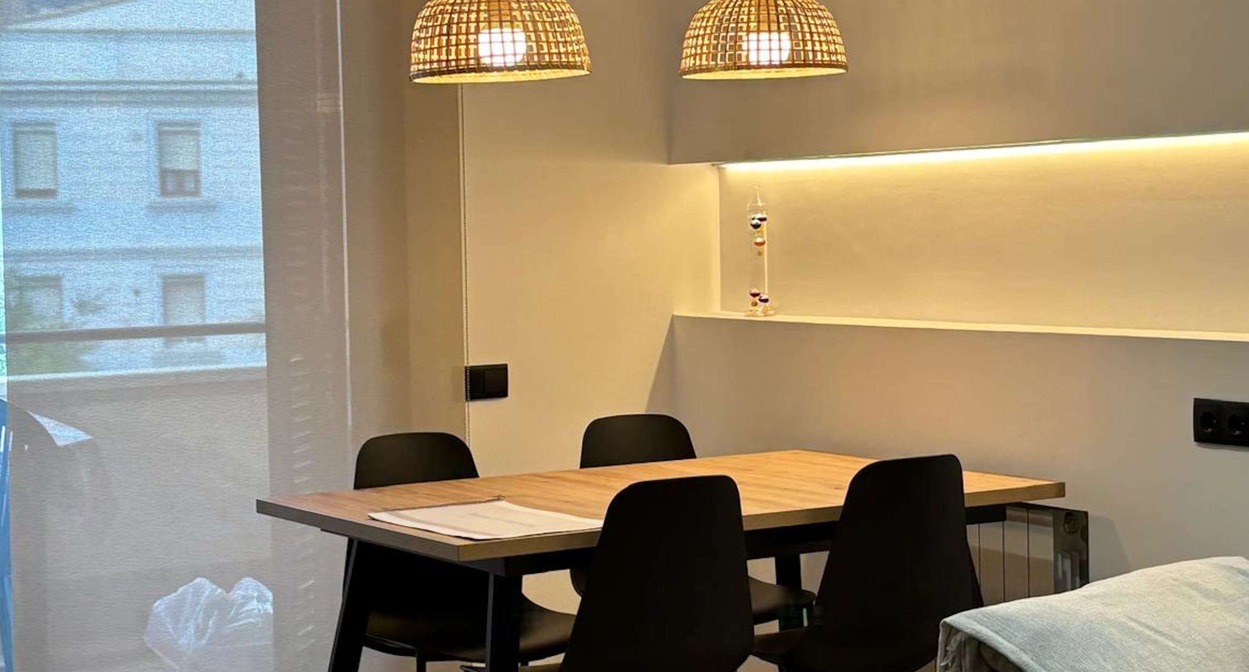 Comedor moderno con mesa de madera y lámparas colgantes de mimbre