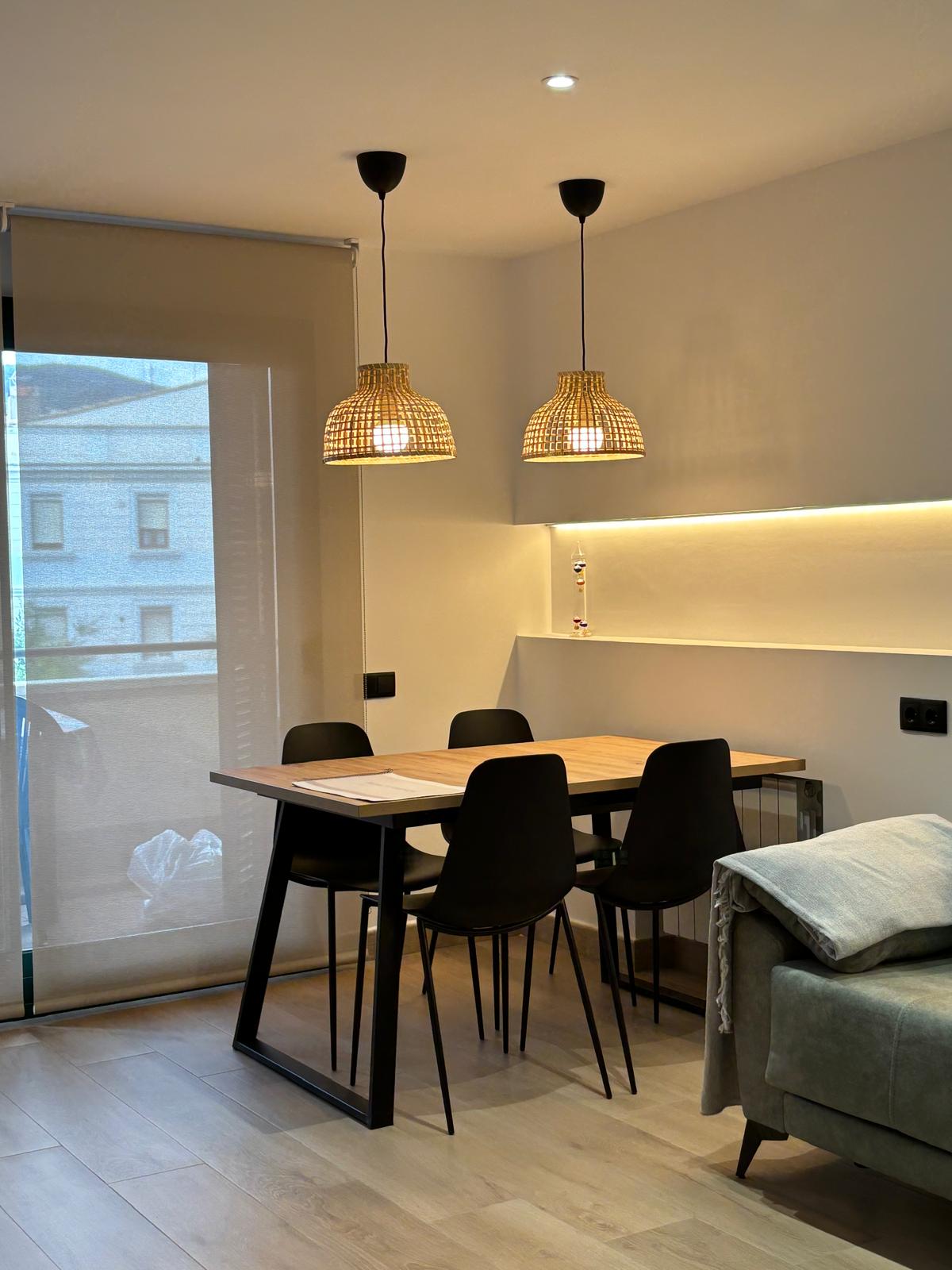 Comedor moderno con mesa de madera y lámparas colgantes de mimbre